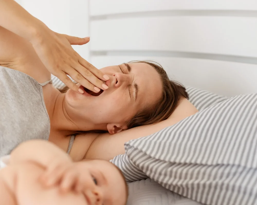 indoor-shot-sleepy-mother-lying-bed-with-infant-baby-daughter-son-woman-yawning-covering-mouth-with-hand-has-sleepless-night-needs-energy indoor-shot-sleepy-mother-lying-bed-with-infant-baby-daughter-son-woman-yawning-covering-mouth-with-hand-has-sleepless-night-needs-energy